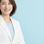 低酸素性虚血性脳症（HIE）のある子どもの痙攣・筋緊張・体温調節と入浴について説明する白ジャケット姿の女性アドバイザーの横長写真