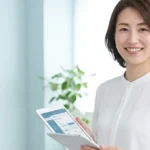 脊髄性筋萎縮症（SMA）タイプ別の安全な入浴方法を解説する白ブラウスを着てタブレットを持つ女性アドバイザーの横長写真